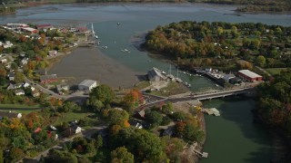 AX148_071 - 6K aerial stock footage flying by small town, small bridge, warehouses, autumn, Thomaston, Maine