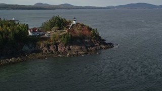 AX148_081E - 6K aerial stock footage flying over fall foliage, revealing Owls Head Light, autumn, Owls Head, Maine