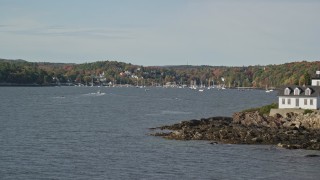 6K aerial stock footage flying by Indian Island Light to Lockport Harbor, small town, autumn, Rockport, Maine Aerial Stock Footage | AX148_090E