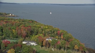 AX148_103 - 6K aerial stock footage flying by foliage, a sailboat, West Penobscot Bay, autumn, Rockport, Maine