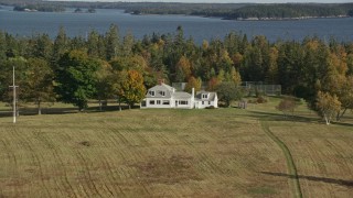 AX148_134E - 6K aerial stock footage approaching an isolated home, tennis court, tilt down, autumn, Hog Island, Maine