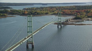 AX148_141E - 6K aerial stock footage orbiting the Deer Isle Bridge near a shore with trees, autumn, Deer Isle Bridge, Maine