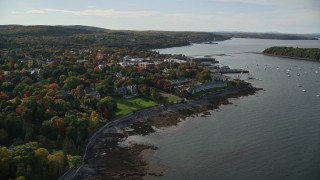 AX148_217E - 5.5K aerial stock footage flying over fall foliage in a small coastal town toward harbor, autumn, Bar Harbor, Maine