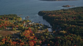 AX149_013E - 5.5K aerial stock footage flying by coastal neighborhood among fall foliage, Blue Hill, Maine