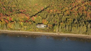 5.5K aerial stock footage flying by isolated waterfront home, colorful forest, autumn, Castine, Maine Aerial Stock Footage | AX149_086E