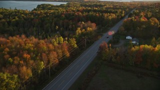 5.5K aerial stock footage tracking car on road through forest in autumn, Stockton Springs, Maine, sunset Aerial Stock Footage | AX149_130E