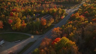 AX149_132E - 5.5K aerial stock footage tracking car on road through forest, autumn, Stockton Springs, Maine, sunset