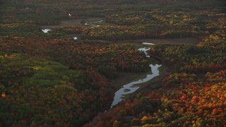 5.5K aerial stock footage flying by river through a colorful forest in autumn, Liberty, Maine, sunset Aerial Stock Footage | AX149_189