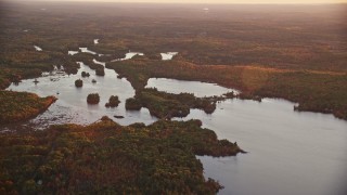 5.5K aerial stock footage flying by Togus Pond, dense colorful forest, autumn, Augusta, Maine, sunset Aerial Stock Footage | AX149_209E