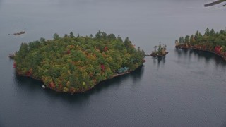 5.5K aerial stock footage flying by Sheep Island waterfront home, colorful trees, Kezar Lake, autumn, Lovell, Maine Aerial Stock Footage | AX150_139E