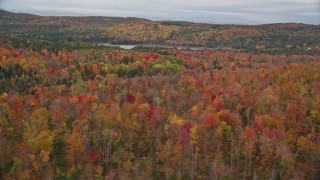 AX150_333E - 5.5K aerial stock footage flying over colorful forest, approach Thurman W Dix Reservoir, autumn, Orange, Vermont