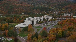 AX150_365E - 5.5K aerial stock footage orbiting large office buildings, grassy clearings, trees in autumn,  Montpelier, Vermont