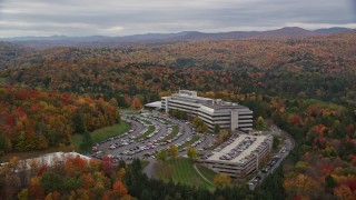 AX150_368E - 5.5K aerial stock footage orbiting brightly colored trees, large office buildings, autumn, Montpelier, Vermont