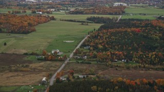 AX150_399 - 5.5K aerial stock footage flying by rural farms, Airport Road, colorful trees, autumn, overcast, Barre, Vermont