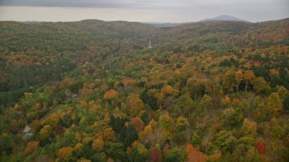 5.5K aerial stock footage flying over brightly colored forested hills, approach rural homes, autumn, Taftsville, Vermont Aerial Stock Footage | AX151_037E