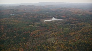 5.5K aerial stock footage flying over forested hills, approaching pond, overcast, autumn, Croydon, New Hampshire Aerial Stock Footage | AX151_071E