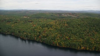 AX151_127E - 5.5K aerial stock footage flying over Lake Winnepocket, dense forest, rural homes in autumn, overcast, Webster, New Hampshire