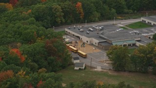 AX152_024 - 5.5K aerial stock footage flying by Hooksett Memorial High School, school buses, autumn, Hooksett, New Hampshire