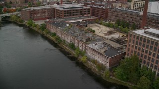 5.5K aerial stock footage flying by riverfront factory, colorful foliage, autumn, Lawrence, Massachusetts Aerial Stock Footage | AX152_096