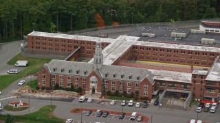 AX152_153 - 5.5K aerial stock footage off a close up approach to a prison surrounded by trees, autumn, Billerica, Massachusetts