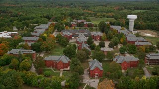 AX152_202E - 5.5K aerial stock footage flying over autumn trees toward Medfield State Hospital, Medfield, Massachusetts