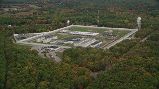 AX152_216E - 5.5K aerial stock footage flying away from Massachusetts Correctional Institution Cedar Junction and fall trees, autumn, Walpole, Massachusetts