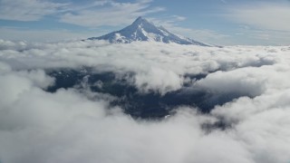 AX154_066E - 5.5K aerial stock footage approaching snowy summit while flying over clouds, Mount Hood, Cascade Range, Oregon