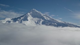 AX154_075E - 5.5K aerial stock footage of a slow approach to snowy Mount Hood, surrounded by clouds, Mount Hood, Cascade Range, Oregon