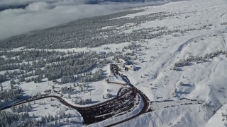 AX154_090E - 5.5K aerial stock footage orbiting Timberline Lodge beside snowy forest on Mount Hood, Cascade Range, Oregon