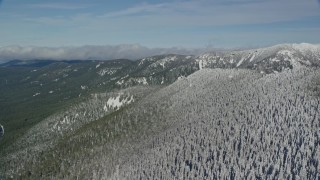 5.5K aerial stock footage panning across evergreen and snowy forest to mountain ridges, Cascade Range, Oregon Aerial Stock Footage | AX154_107