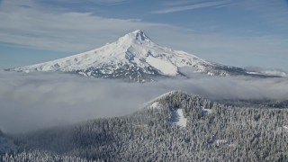 AX154_111E - 5.5K aerial stock footage of low clouds and snowy forest at the base of Mount Hood, Cascade Range, Oregon