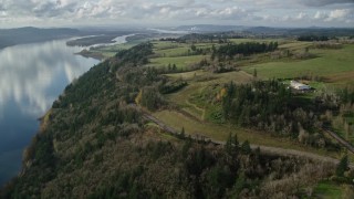 AX154_196 - 5.5K aerial stock footage flying over and tilt to Highway 14 through trees by the Columbia River, Washougal, Washington