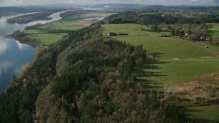 AX154_197E - 5.5K aerial stock footage of a bird's eye view of Highway 14 through forest, tilt to reveal an isolate home and green fields, Washougal, Washington