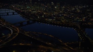 AX155_297 - 5.5K aerial stock footage of Downtown skyscrapers, Willamette River bridges, freeway interchange, and White Stag sign at night, Downtown Portland, Oregon