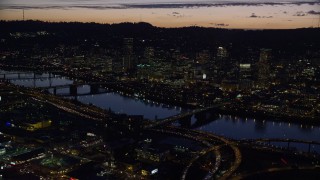 AX155_298 - 5.5K aerial stock footage of a reverse view of downtown skyscrapers, Willamette River bridges, and freeway interchange at night, Downtown Portland, Oregon