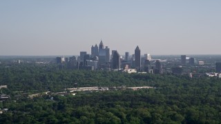 AX38_027 - 4.8K aerial stock footage of a distant shot of Midtown Atlanta skyscrapers beyond trees, Buckhead, Georgia