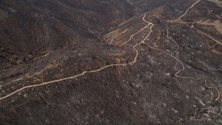 AX42_001 - 5K aerial stock footage fly over fire damage on a mountain ridge with dirt roads, Santa Monica Mountains, California