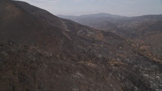 AX42_003E - 5K aerial stock footage pan across scorched slopes of Santa Monica Mountains, California, and fly over them