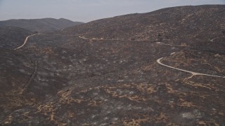 AX42_010 - 5K aerial stock footage approach a mountain road winding around the fire-damaged slopes of Santa Monica Mountains, California