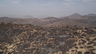 AX42_011 - 5K aerial stock footage fly over a fire-damaged slope to reveal barren, less damaged Santa Monica Mountains, California