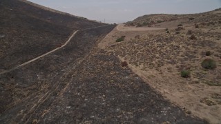 AX42_018 - 5K aerial stock footage fly low to follow a mountain road over a ridge, Santa Monica Mountains, California