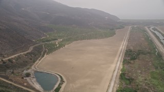 5K aerial stock footage follow a country road to approach crops and farmland in light fog, Point Mugu, California Aerial Stock Footage | AX42_050E