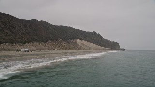 5K aerial stock footage of flying low over Pacific Ocean waves rolling in toward a beach, Malibu, California Aerial Stock Footage | AX42_064E