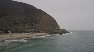 AX42_069 - 5K aerial stock footage of low altitude approach to waves crashing against the beach and rocks, Malibu, California