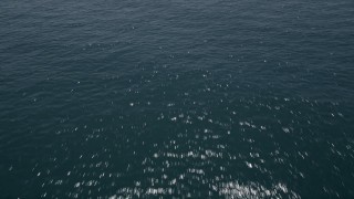 AX42_094 - 5K aerial stock footage of flying low over crystal blue ocean waters, Malibu, California