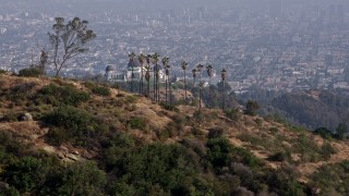 4K aerial stock footage flying by Griffith Observatory, Downtown Los Angeles skyline blanketed in fog in the background, Los Angeles Aerial Stock Footage | AX43_010