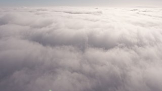 AX43_050 - 4K aerial stock footage flying over a dense marine layer over Los Angeles, California and pan across the clouds