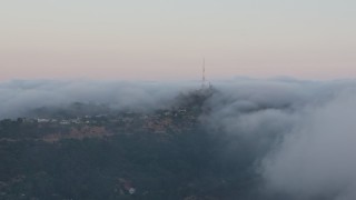 4K aerial stock footage of a radio tower peaking out from marine layer, Hollywood Hills, California, sunset Aerial Stock Footage | AX44_016