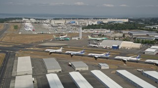 AX45_152E - 5K aerial stock footage of panning across a row of six airliners at Paine Field, reveal Boeing Factory, Washington