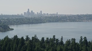 5K aerial stock footage of Downtown Seattle skyline in the far distance beyond the tree-covered Bailey Peninsula, Washington Aerial Stock Footage | AX47_007E